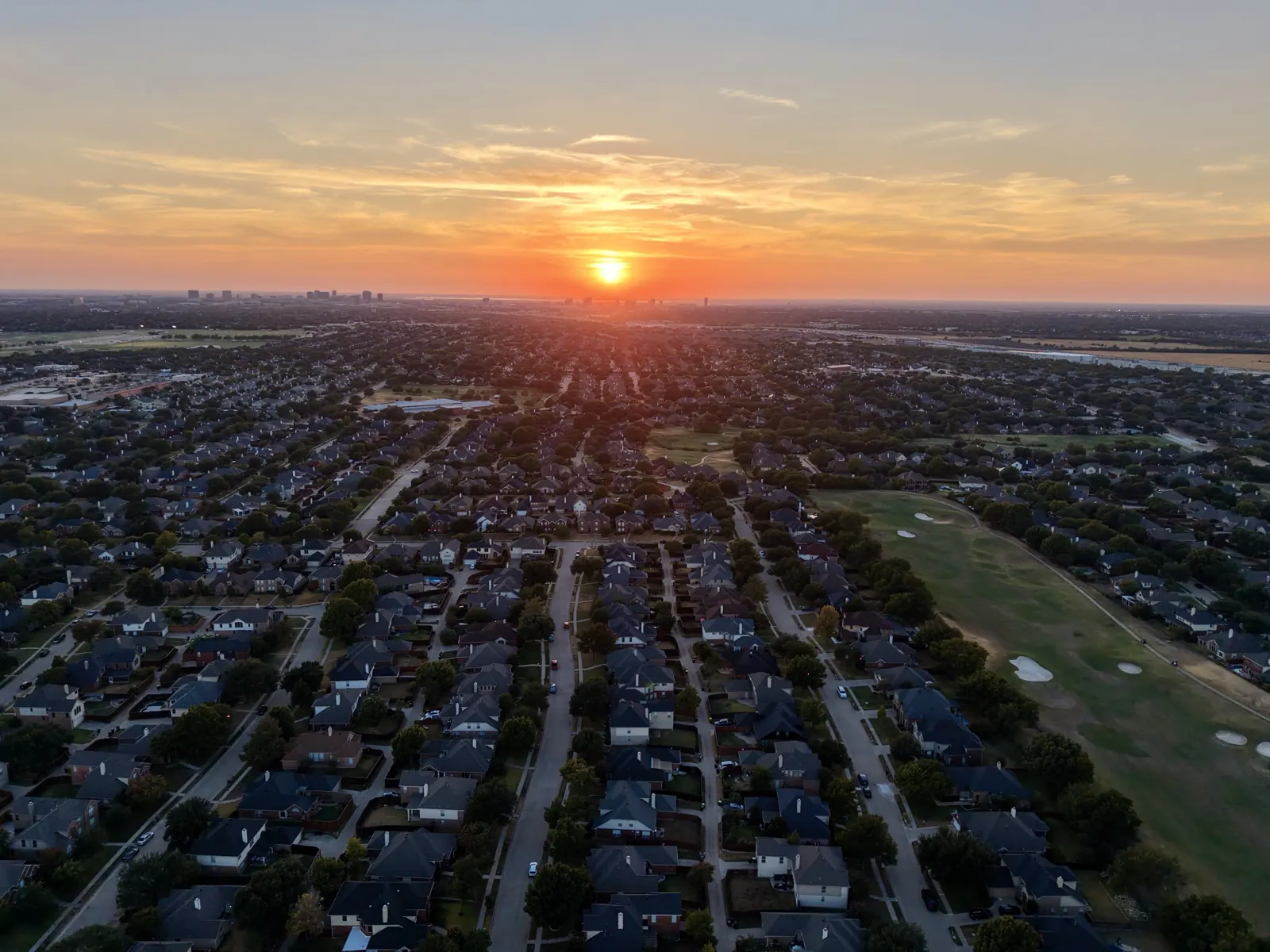 Sunset over North Texas neighborhoods and the Dallas skyline, shot by drone